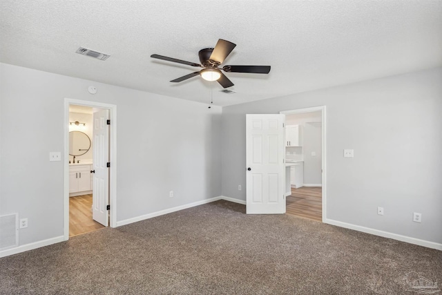 unfurnished bedroom featuring a textured ceiling, carpet flooring, ceiling fan, and ensuite bathroom