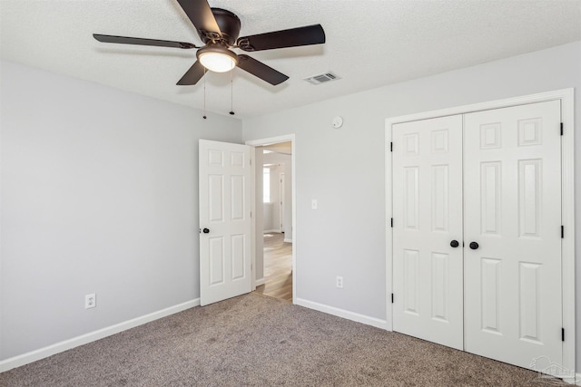 unfurnished bedroom featuring a closet, a textured ceiling, light carpet, and ceiling fan