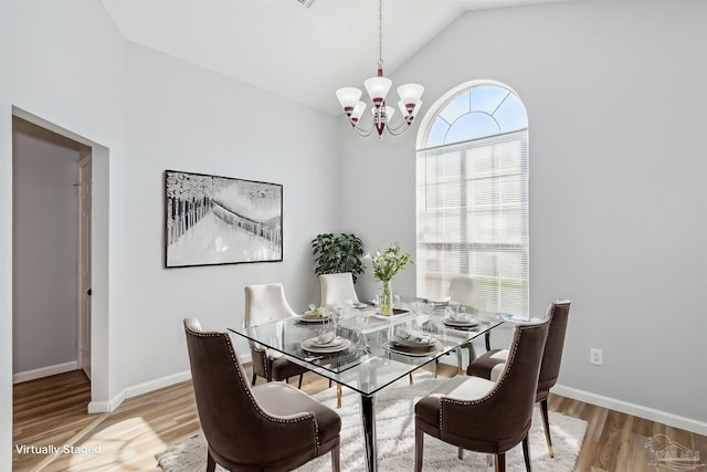 dining area featuring lofted ceiling, an inviting chandelier, and hardwood / wood-style flooring