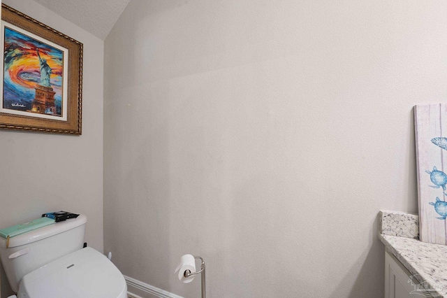 bathroom with a textured ceiling, vanity, and toilet