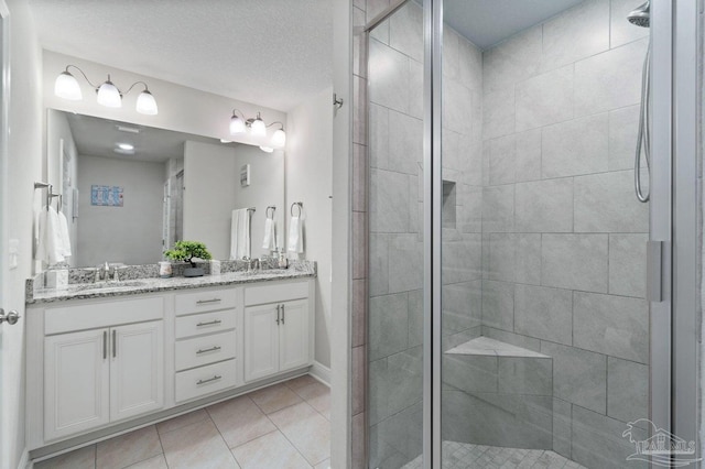 bathroom featuring tile patterned floors, a shower with door, vanity, and a textured ceiling