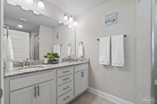 bathroom with tile patterned flooring, vanity, a shower with shower door, and a textured ceiling