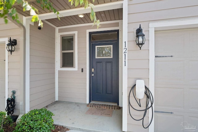 view of exterior entry with a garage and covered porch