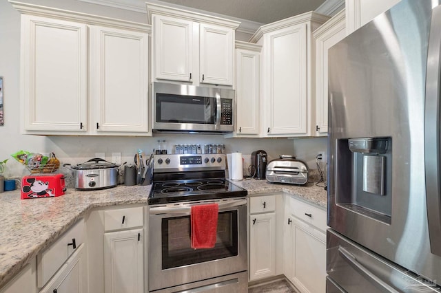 kitchen featuring light stone countertops, appliances with stainless steel finishes, and white cabinetry