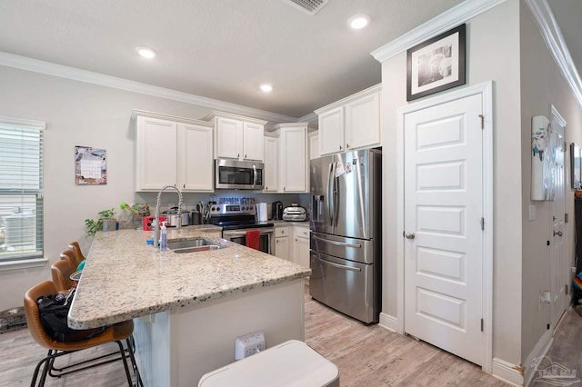 kitchen featuring a breakfast bar, stainless steel appliances, white cabinetry, and ornamental molding