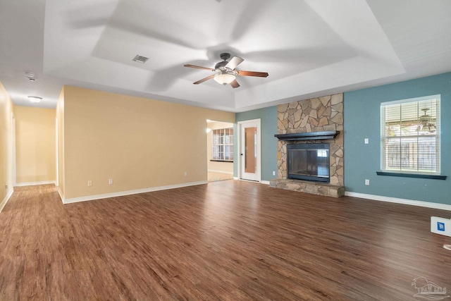 unfurnished living room featuring hardwood / wood-style floors, ceiling fan, a fireplace, and a raised ceiling