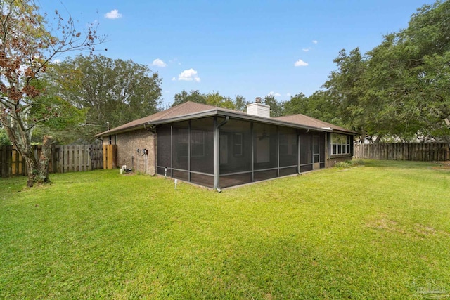 rear view of house featuring a yard and a sunroom