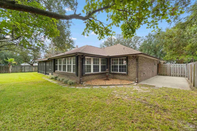 rear view of property featuring a sunroom, a patio area, and a lawn