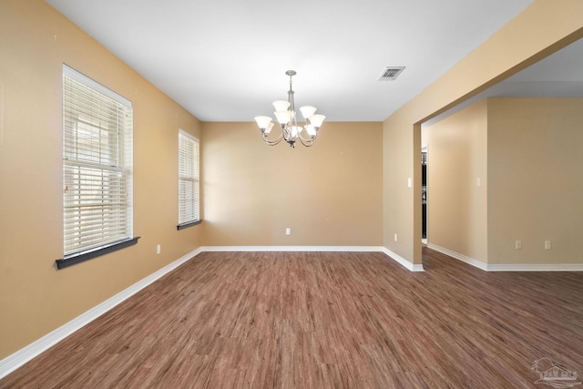 empty room with a notable chandelier and hardwood / wood-style flooring