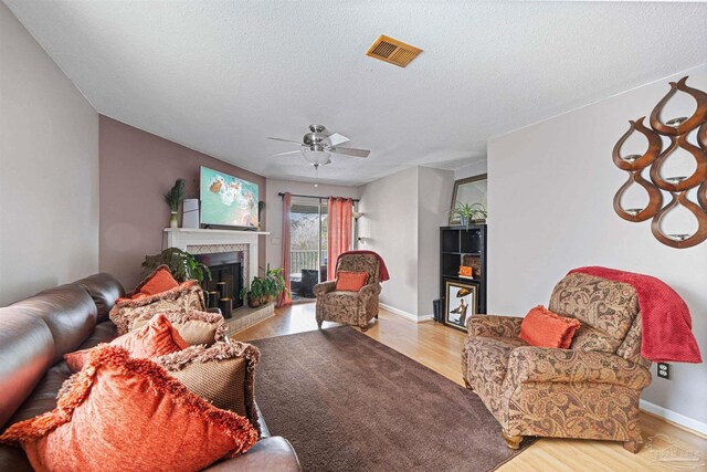 living room with ceiling fan, light hardwood / wood-style flooring, and a textured ceiling