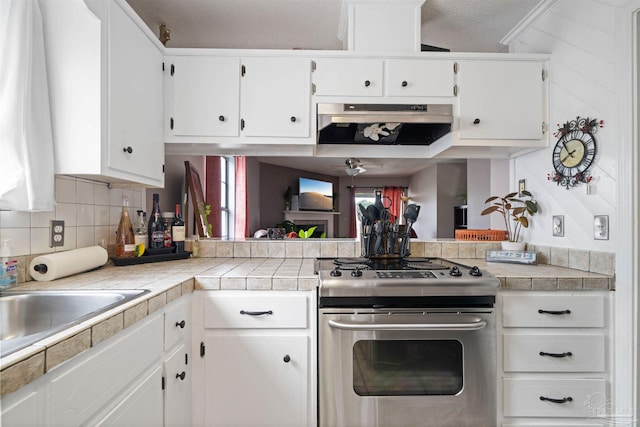 kitchen with ceiling fan, extractor fan, stainless steel range, white cabinets, and tile countertops