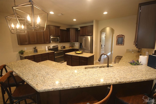 4135 Dundee Crossing Dr, Pace, FL 32571 - kitchen with appliances with stainless steel finishes, a sink, dark brown cabinets, arched walkways, and light stone countertops