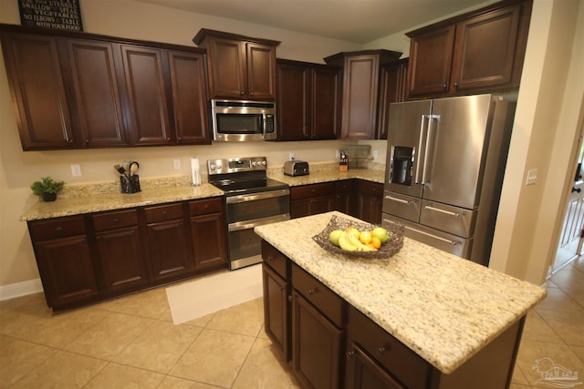 4135 Dundee Crossing Dr, Pace, FL 32571 - kitchen featuring stainless steel appliances, light stone countertops, dark brown cabinetry, and light tile patterned floors