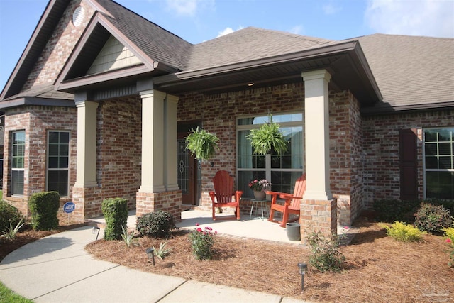 4135 Dundee Crossing Dr, Pace, FL 32571 - view of exterior entry with covered porch, a shingled roof, and brick siding