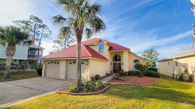 mediterranean / spanish house featuring metal roof, a garage, driveway, stucco siding, and a front yard