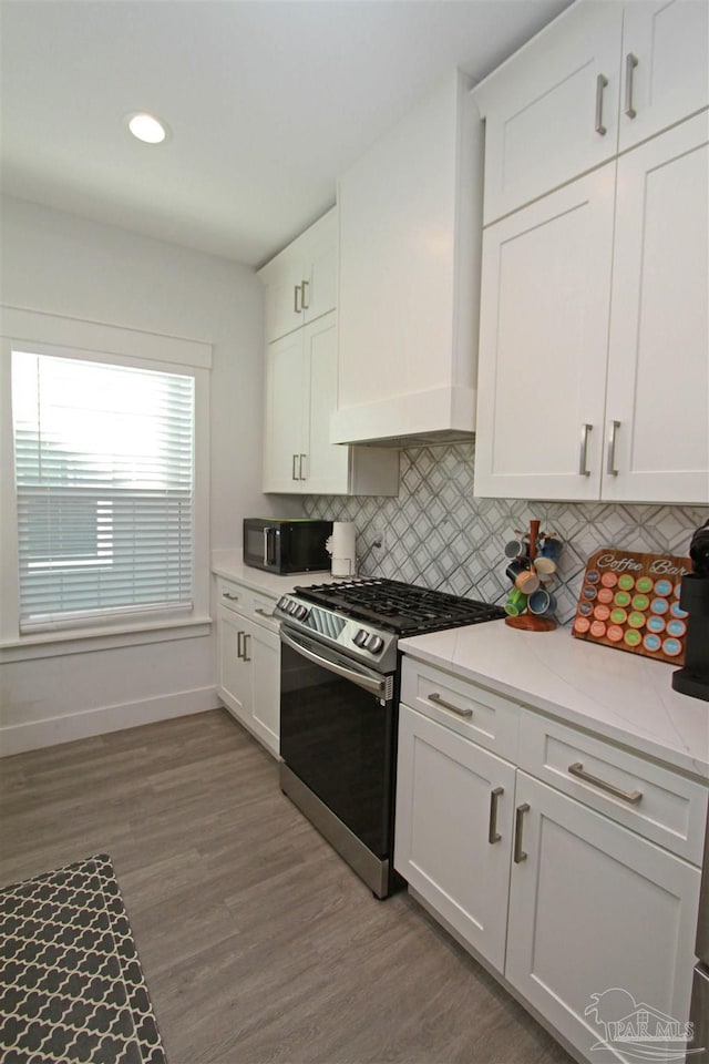 kitchen with gas stove, white cabinetry, backsplash, light hardwood / wood-style floors, and custom range hood