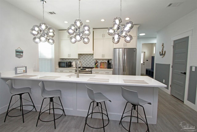 kitchen featuring a kitchen breakfast bar, stainless steel appliances, white cabinetry, and dark wood-type flooring