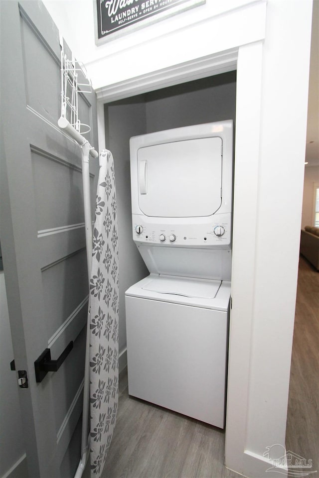 laundry area featuring hardwood / wood-style flooring and stacked washer and clothes dryer