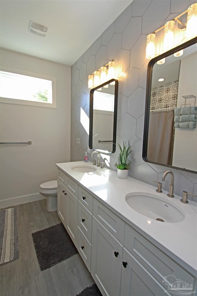 bathroom with decorative backsplash, hardwood / wood-style floors, vanity, and toilet