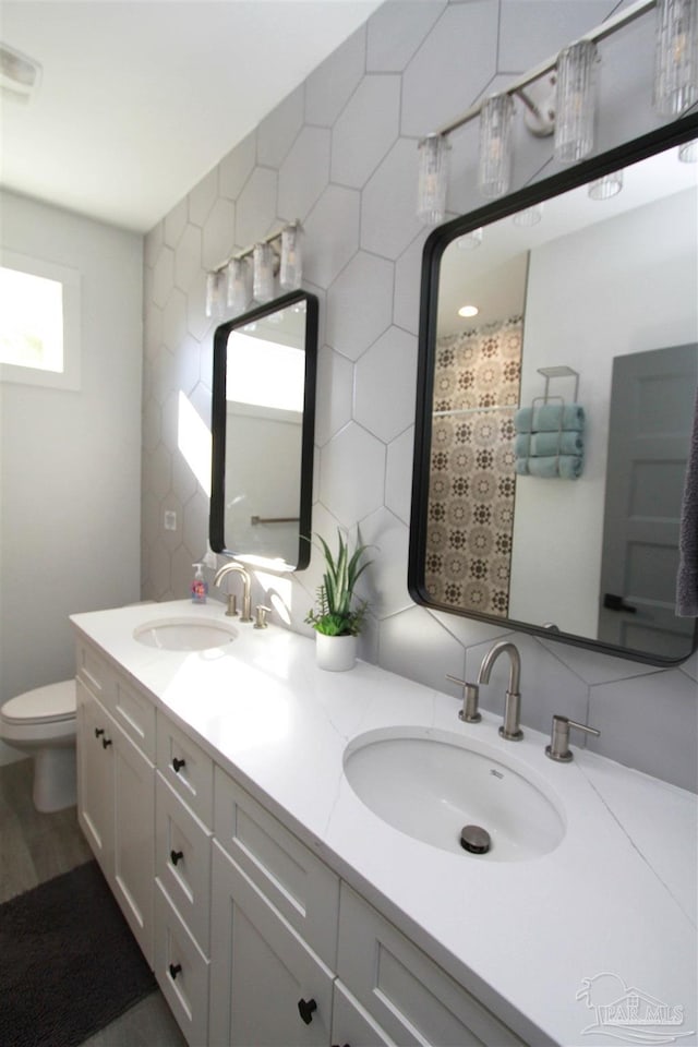 bathroom with decorative backsplash, toilet, and vanity