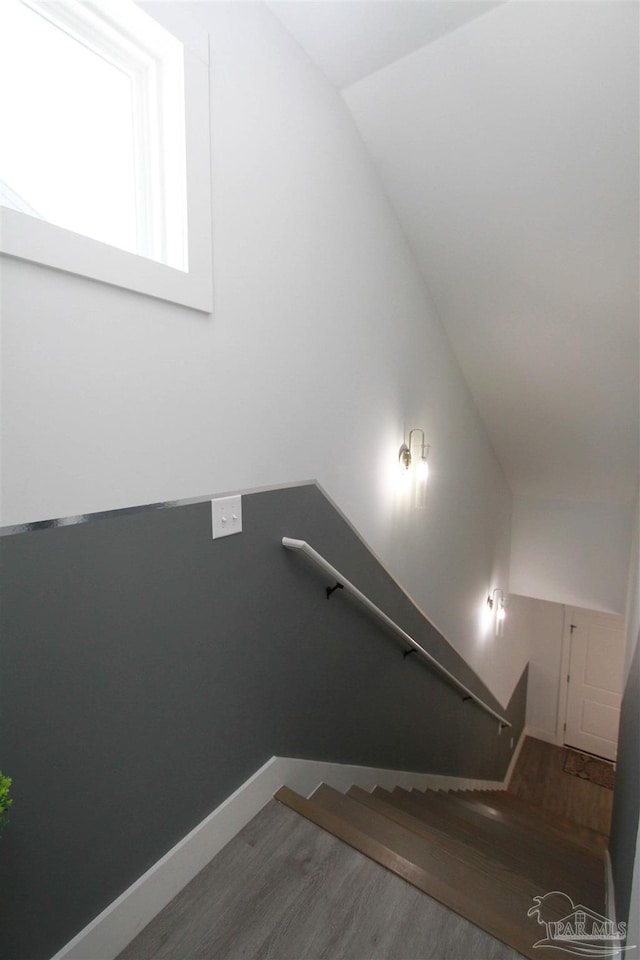 staircase featuring wood-type flooring and vaulted ceiling