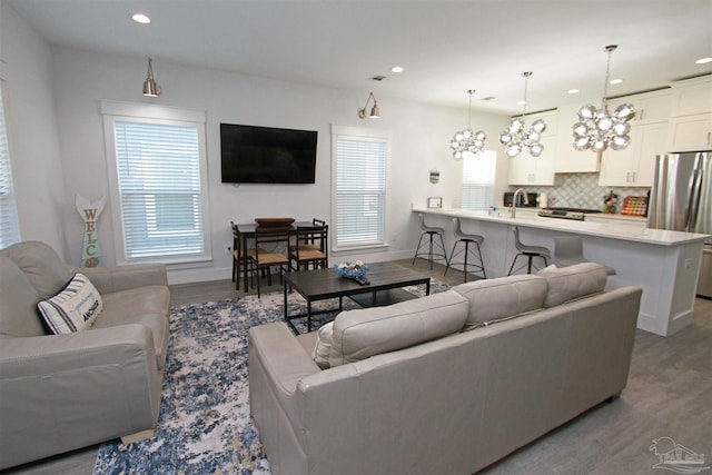 living room featuring sink, light hardwood / wood-style flooring, and a notable chandelier