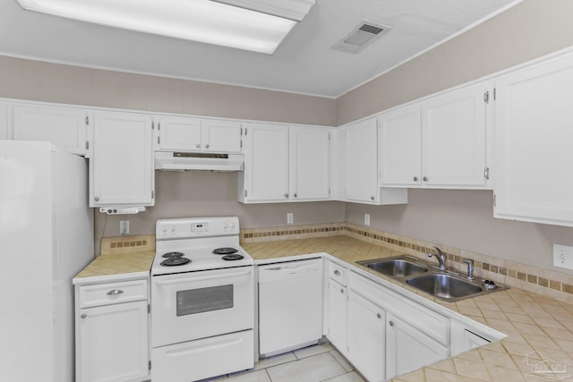 kitchen featuring white appliances, visible vents, under cabinet range hood, white cabinetry, and a sink