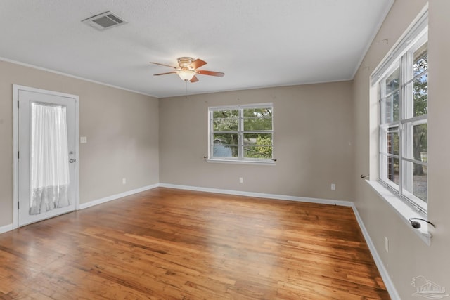 unfurnished room with visible vents, baseboards, light wood-style flooring, ceiling fan, and crown molding