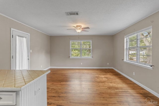 unfurnished room with baseboards, visible vents, a textured ceiling, and light wood finished floors