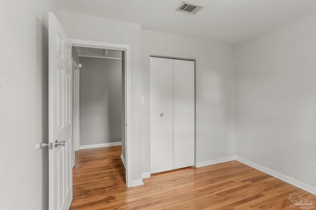 unfurnished bedroom featuring light wood-style flooring, a closet, visible vents, and baseboards