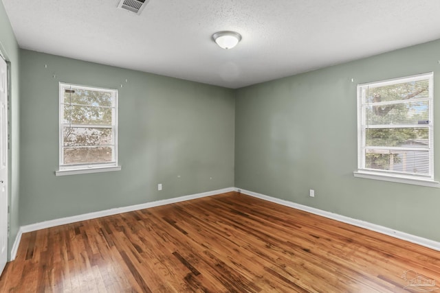 empty room featuring visible vents, baseboards, and wood finished floors