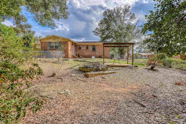 rear view of property featuring fence and brick siding