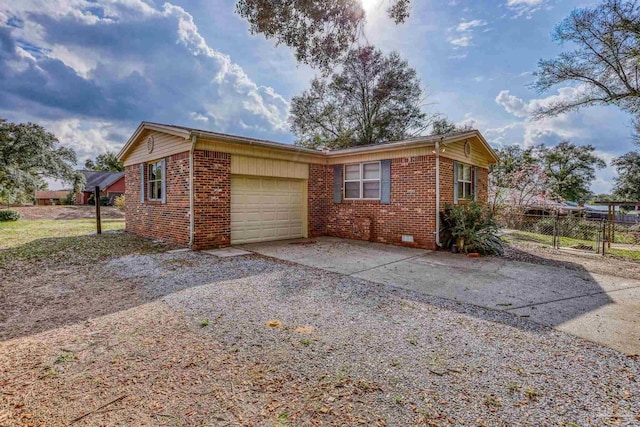 view of home's exterior with driveway, an attached garage, fence, and brick siding