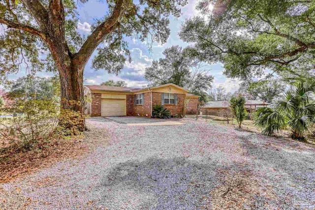 ranch-style home featuring driveway, brick siding, and an attached garage