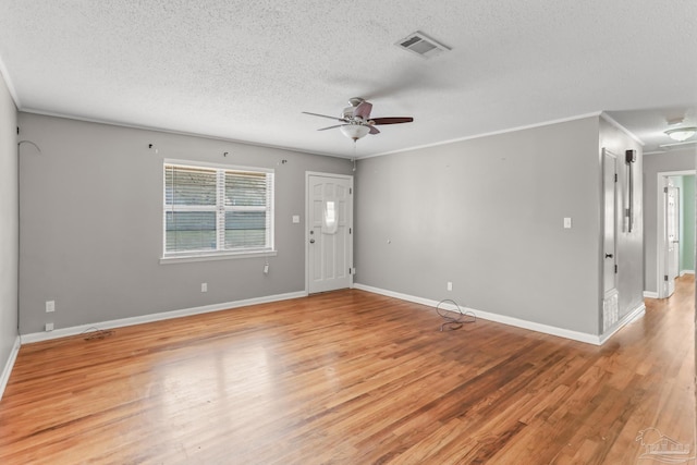 spare room with light wood-style floors, baseboards, visible vents, and ornamental molding