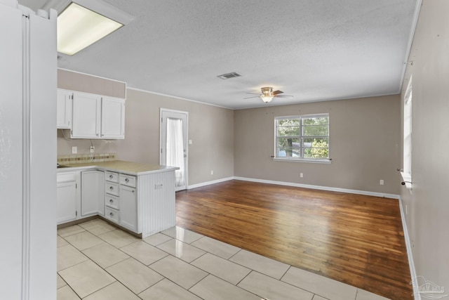 kitchen with visible vents, white cabinets, open floor plan, a peninsula, and light countertops