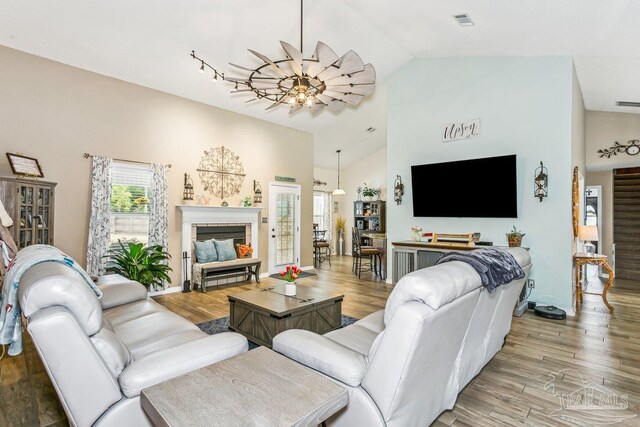 living area featuring wood finished floors, high vaulted ceiling, and a fireplace