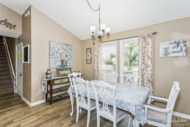 dining space featuring a chandelier, stairway, vaulted ceiling, wood finished floors, and baseboards