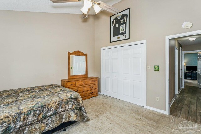 carpeted bedroom featuring a closet, ceiling fan, baseboards, and a high ceiling