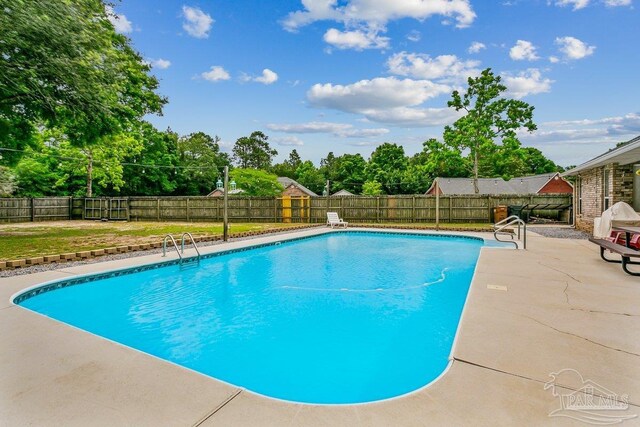 view of swimming pool featuring a patio, a fenced backyard, and view of scattered trees