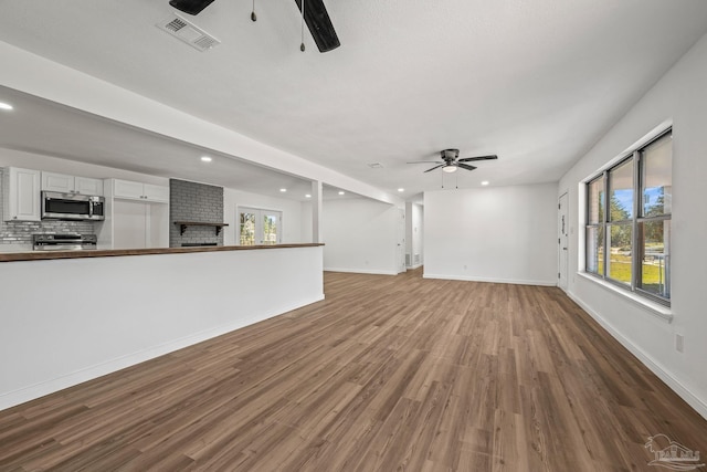 unfurnished living room featuring visible vents, ceiling fan, baseboards, and wood finished floors