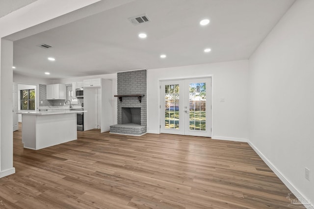 unfurnished living room with baseboards, a fireplace, visible vents, and wood finished floors