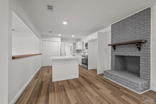 kitchen with visible vents, appliances with stainless steel finishes, wood finished floors, a center island, and light countertops