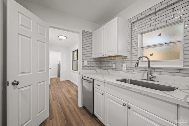 kitchen featuring dark wood-style flooring, a sink, white cabinetry, stainless steel dishwasher, and light stone countertops