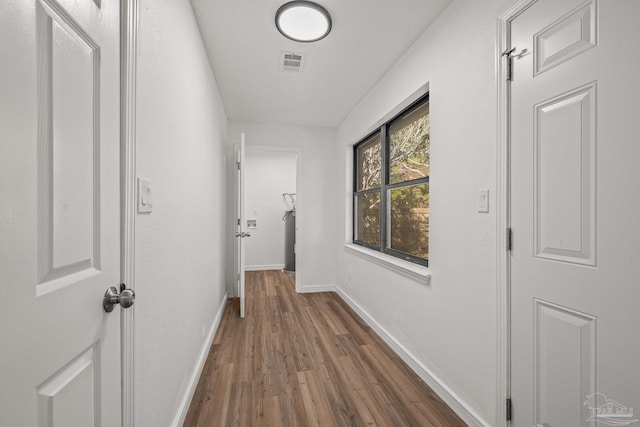 hallway featuring dark wood finished floors, visible vents, and baseboards