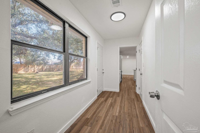 hall featuring visible vents, baseboards, and wood finished floors