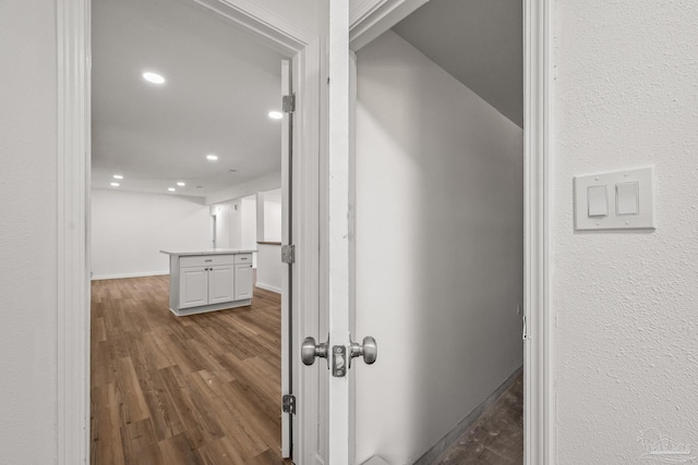 corridor featuring dark wood-type flooring, recessed lighting, and baseboards