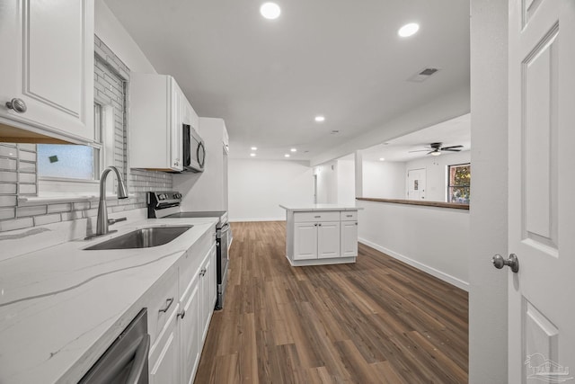 kitchen with white cabinets, decorative backsplash, appliances with stainless steel finishes, dark wood-style flooring, and a sink