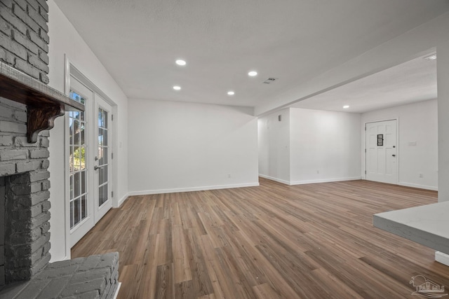 unfurnished living room featuring recessed lighting, wood finished floors, visible vents, baseboards, and a brick fireplace