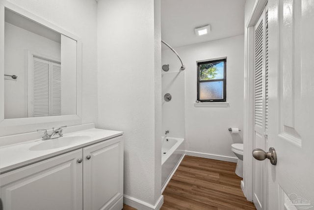 bathroom featuring toilet, wood finished floors, vanity, baseboards, and shower / washtub combination